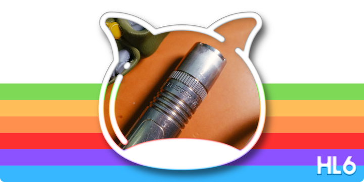 Featured image of the Flieger flashlight inside the foofaraw logo outline on top of a rainbow background